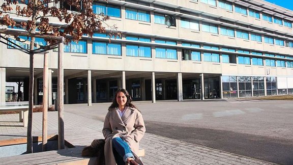 Frau sitzt auf Bänken vor der Schule