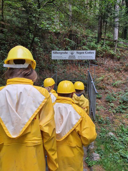 Schüler in gelben Regenmänteln auf dem Weg in den Stollen