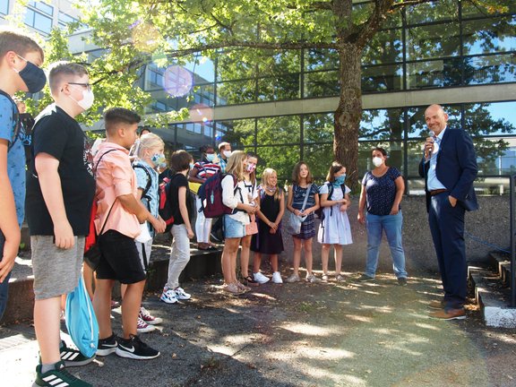 Schulleiter spricht zu Fünftklässlern im Halbkreis