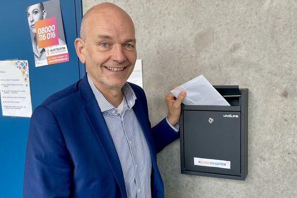 Schulleiter vor dem Briefkasten, wirft Brief ein