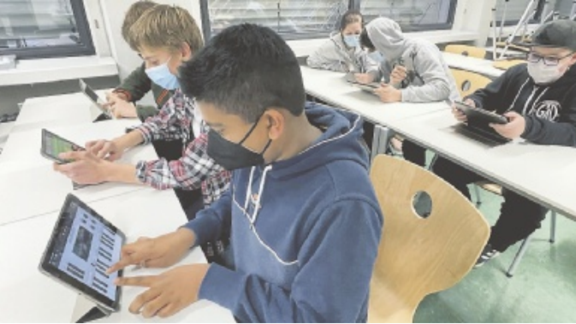 Schüler sitzen vor iPad