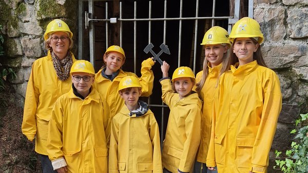 Gruppenfoto der Schüler in gelben Regenjacken vor dem Stolleneingang