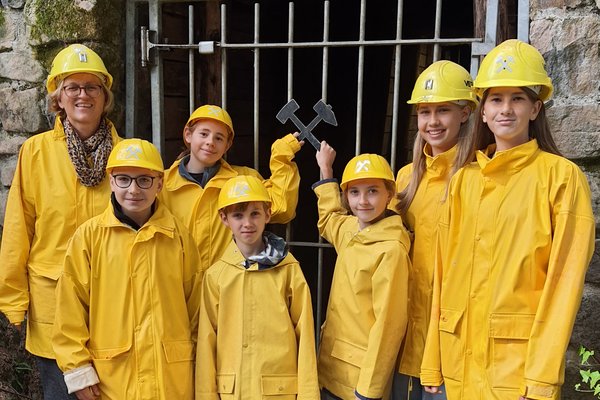Gruppenfoto der Schüler in gelben Regenjacken vor dem Stolleneingang