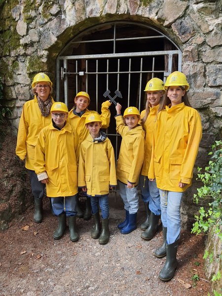 Gruppenfoto der Schüler in gelben Regenjacken vor dem Stolleneingang