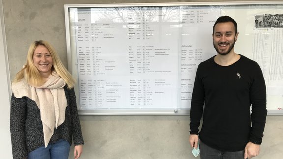 zwei Referendare vor Info-Tafel