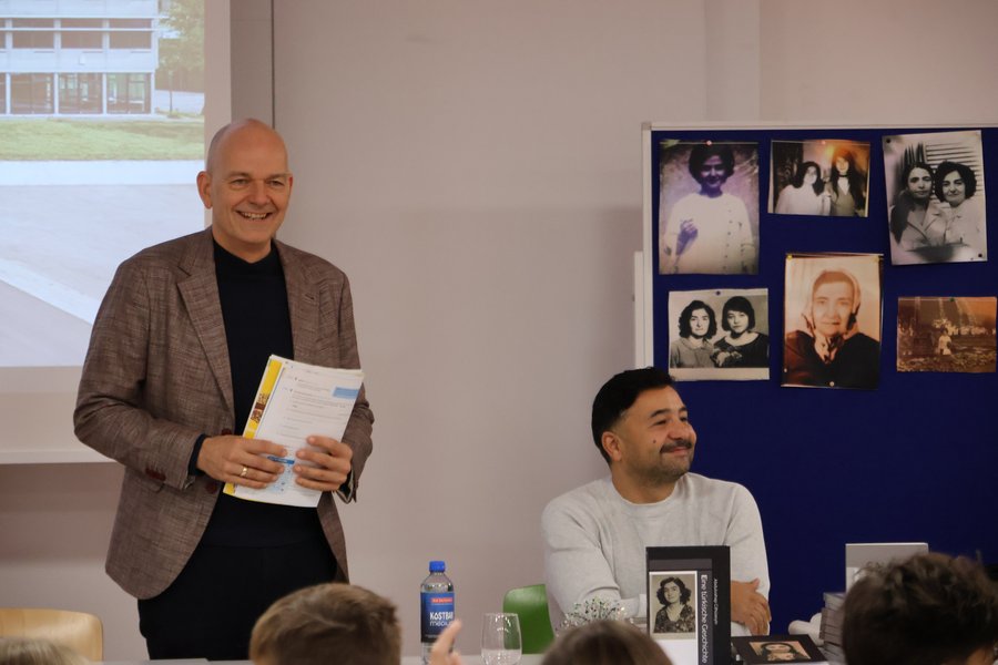 Autor liest aus seinem Buch mit Publikum und Schulleiter